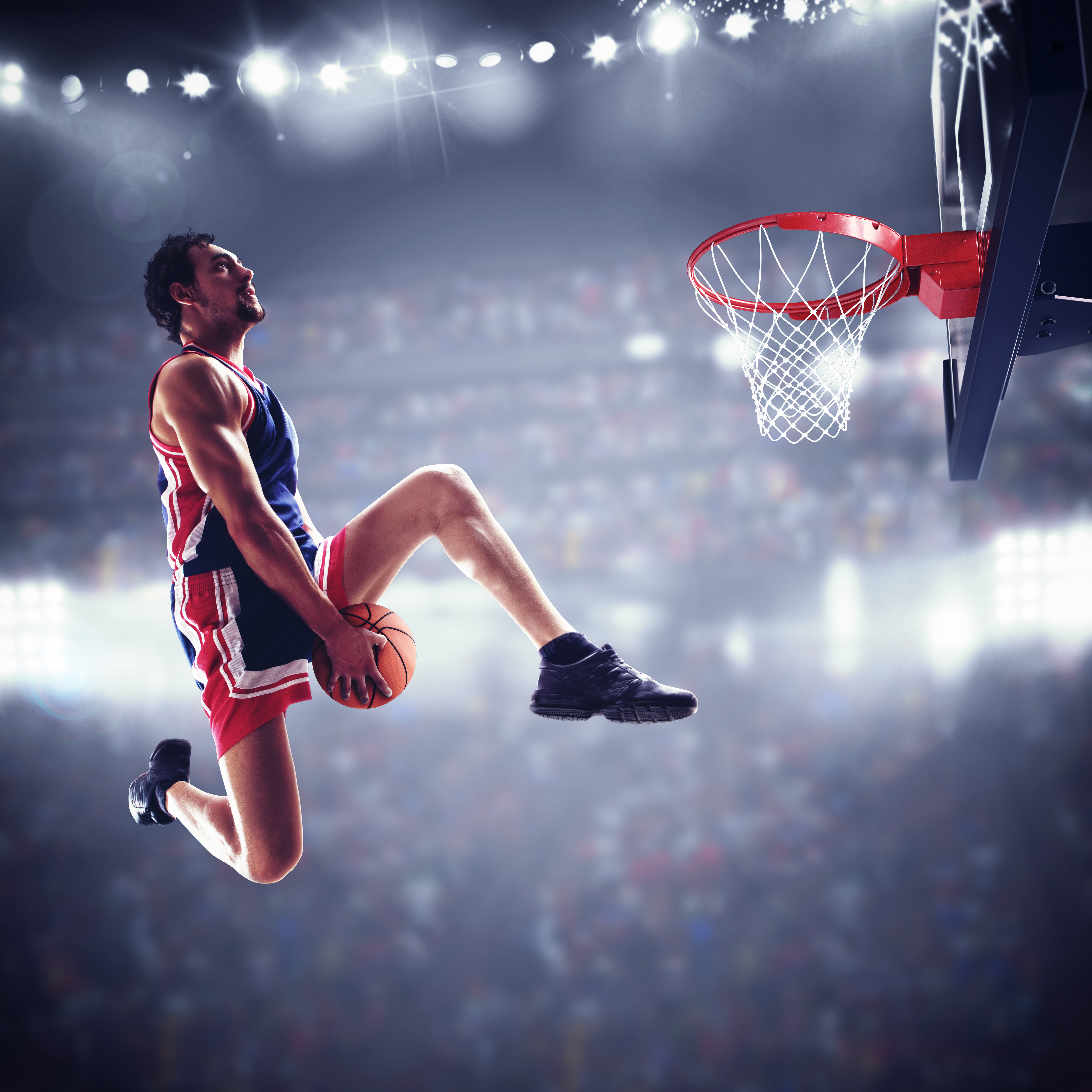 Basketball player throwing ball in stadium with spectators